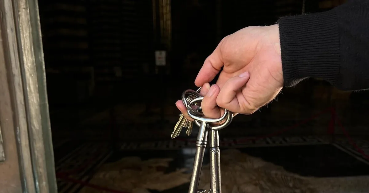 A hand holding the large old iron keys of Siena Cathedral in a doorway