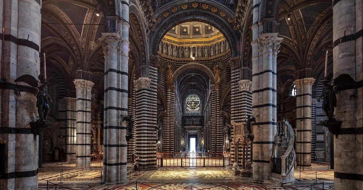 The nave of Siena Cathedral with its black-and-white striped columns and the inlaid marble floor uncovered